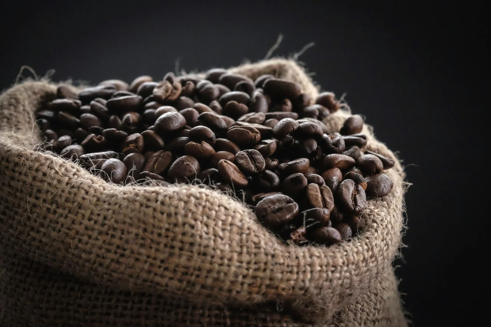 Roasted coffee beans spilling from a burlap sack